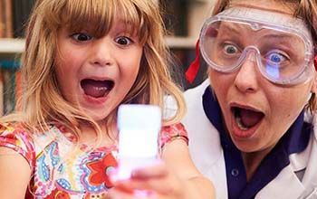 Excited girl and Mad Scientist looking at beaker filled with white liquid