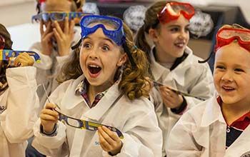 a group of amazed kids wearing diffraction glasses